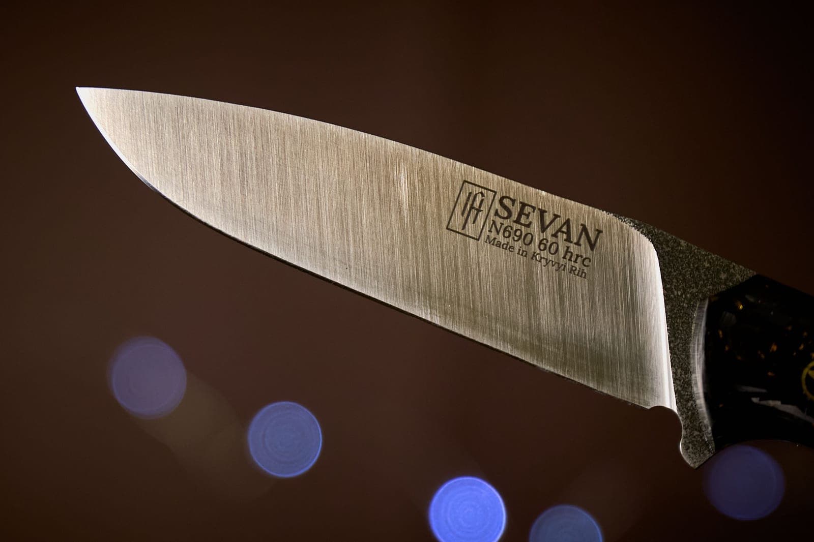 Close-up of a chef's knife blade edge against a dark steel background